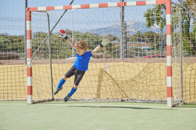 Boy catching ball at football goal
