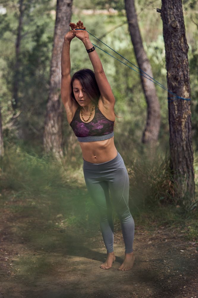 Fit woman stretching elastic band in forest