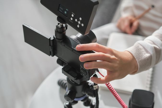 Crop person setting up camera for recording video