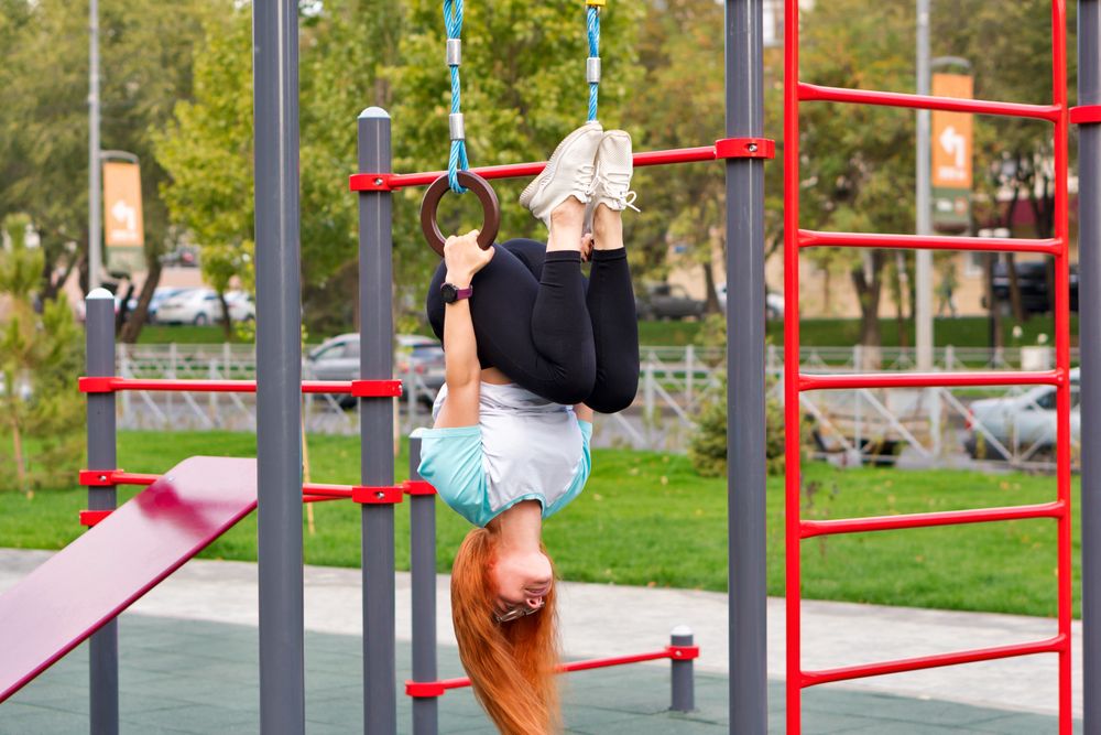 Woman hanging upside down from gym rings in outdoor