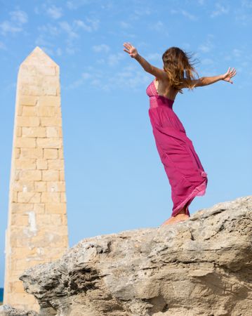Woman in dress standing near stone monument