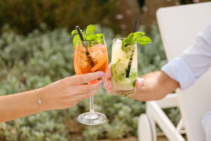 Crop couple clinking glasses with summer cocktails