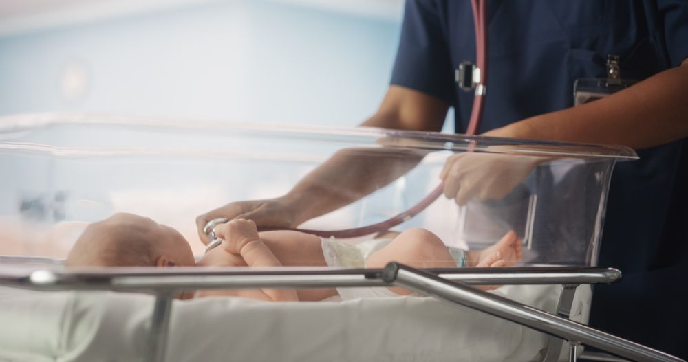 Black Head Nurse Uses Stethoscope to Listen to Heartbeat and Lungs of Recovering Newborn Baby Resting in Bed.