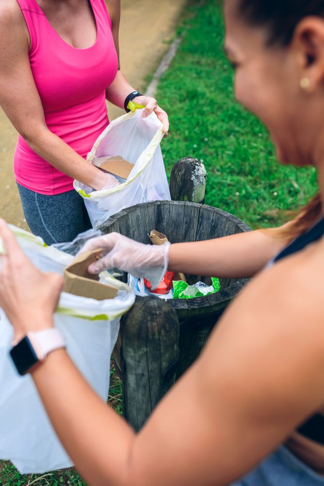 Two women throwing garbage after picking up litter