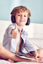 Boy with tablet in headphones showing thumb up
