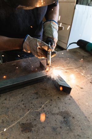 Crop master welding metal pieces at workbench