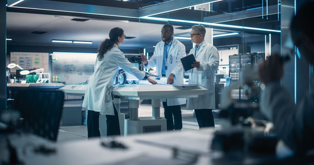 Male Engineer In Lab Coat Discussing an Automated AI Robotic Delivery Assistant with His Young Team