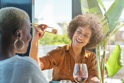 Happy Black Latina female enjoying lunch in cafeteria
