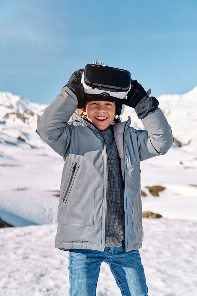 Smiling boy in VR headset in winter mountains