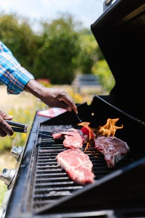 Person in plaid shirt grilling meat