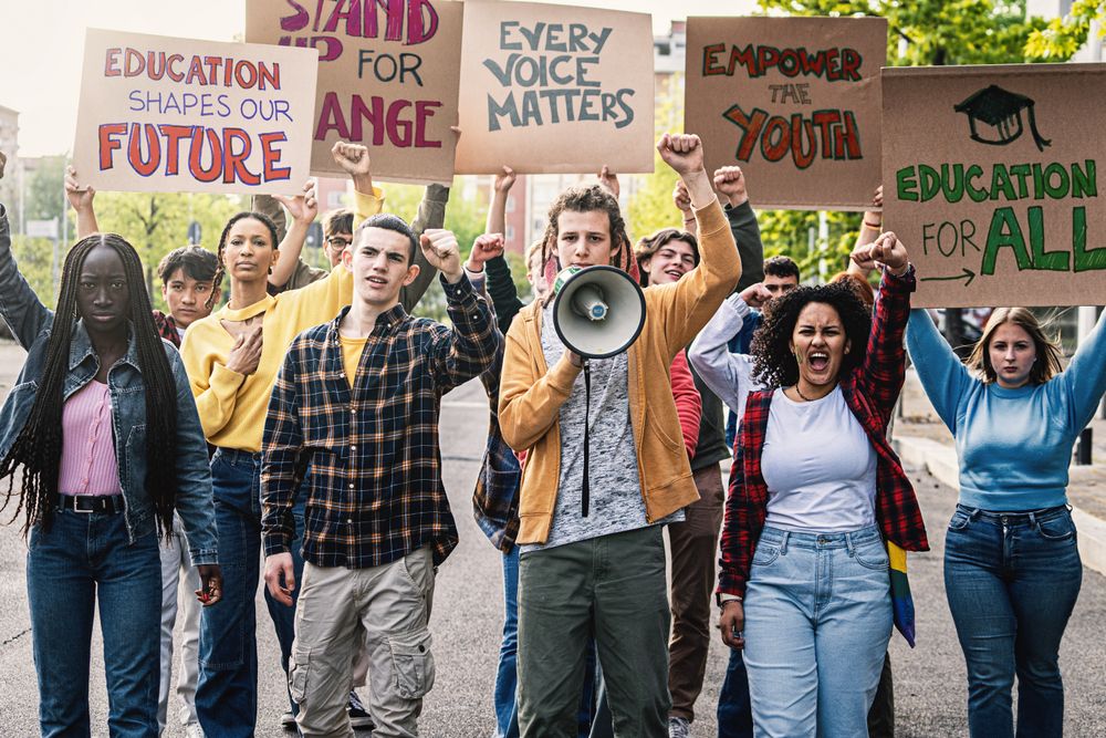 A diverse group of students marching on the street, raising clenched fists