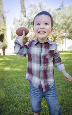 Cute Biracial Boy Playing Football Outside