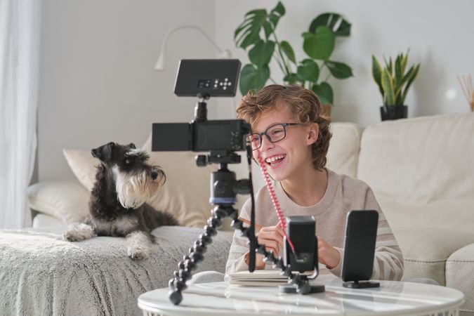 Boy having fun while shooting video for blog at home