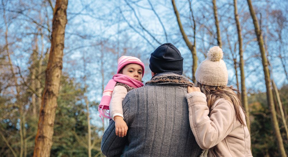 Father holding up young daughter as they stand looking at fall with space for text