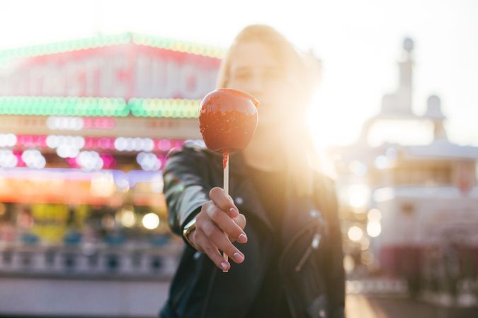 Backlit woman with a candied apple in fairground