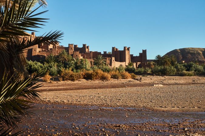 Ancient stone buildings near palms and water