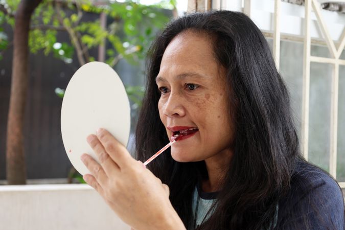 Asian Woman Applying Lipstick