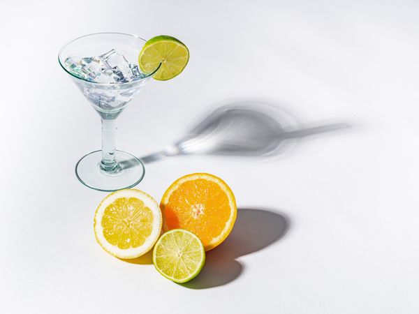 Cocktail glass with ice cubes and sliced citrus