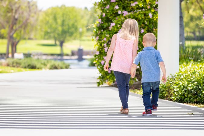 Young Sister and Brother Holding Hands And Walking At The Park