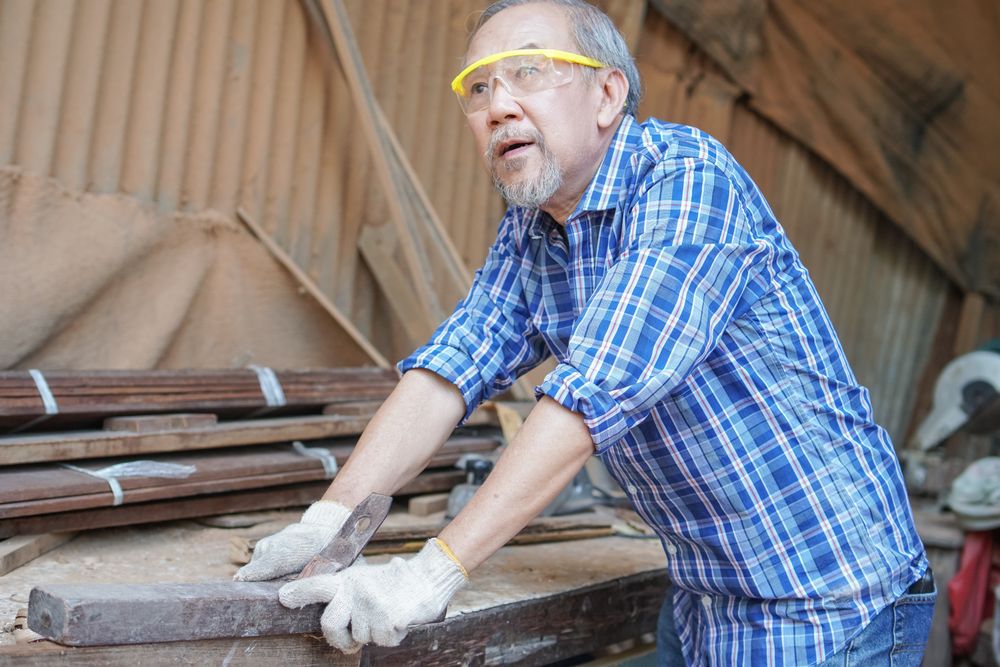 Asian male carpenter with a wooden panel in the shop