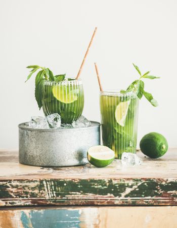 Iced green drinks with lime and mint, with eco friendly straws on light background