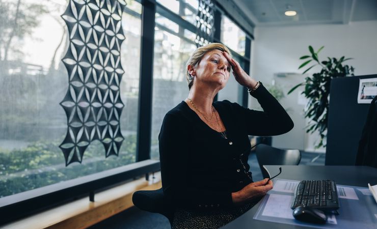 Older professional woman looking tired after working all day on her computer