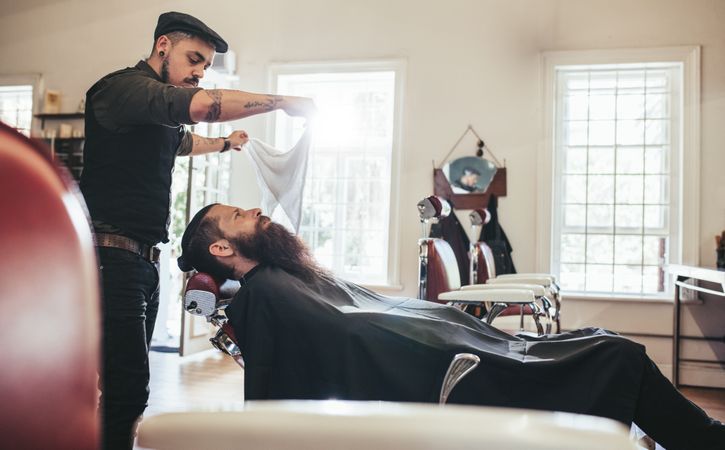 Barber applying towel to customer lying down in chair