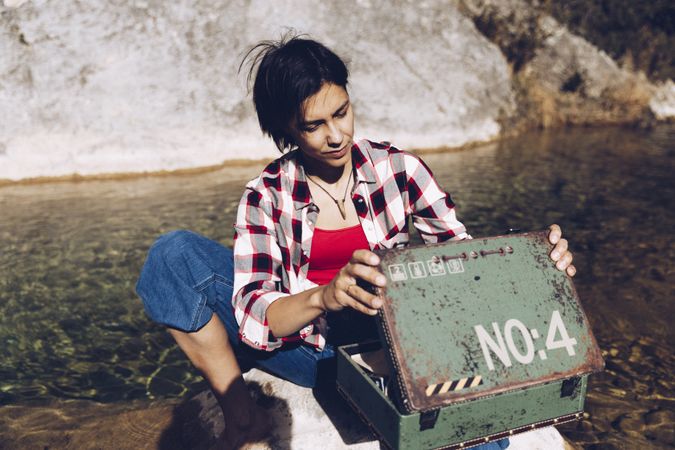 Woman with picnic case on rock in water