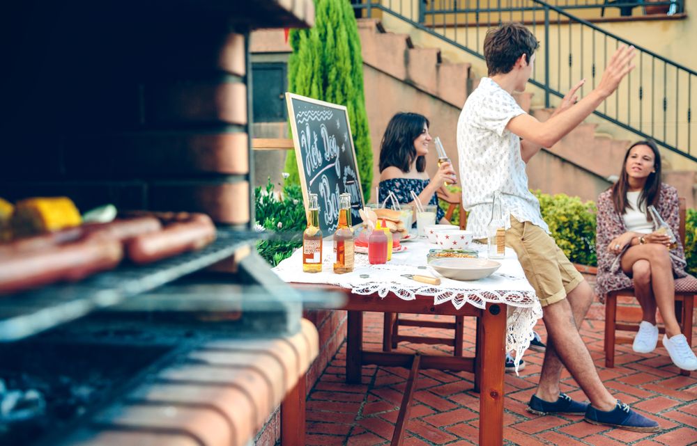 Young people talking outdoors with meal cooking on the grill
