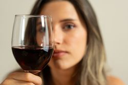 A woman is holding a wine glass and looking at the camera