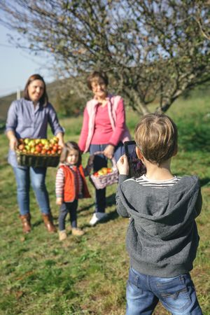 Boy taking photo of family with apples in basket