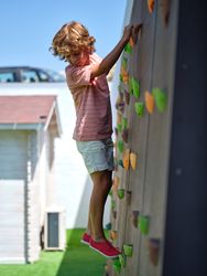 Little boy climbing wall while looking down