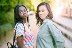 Female friends in casual clothing posing in park walk way