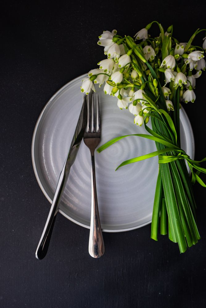 Table setting for Easter dinner with snowdrop flowers on grey plate