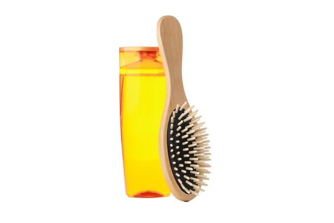 Blank shampoo bottle and hair brush isolated on light background