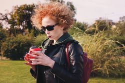 Curly haired woman with coffee outdoors