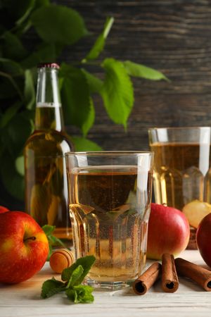 Composition with cider, cinnamon and apples on wooden background