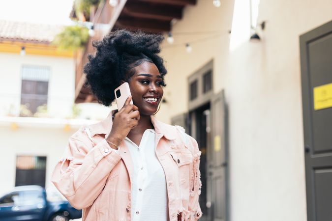 Stylish Black woman walking on the city street talking on the phone