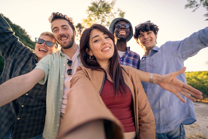 Happy young woman taking a selfie with her diverse group of friends outdoors.