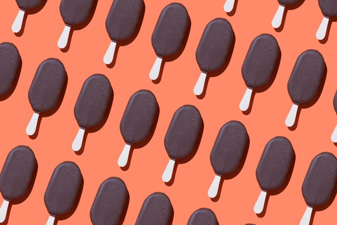 Chocolate popsicle lined up diagonally in diagonal order on an orange background