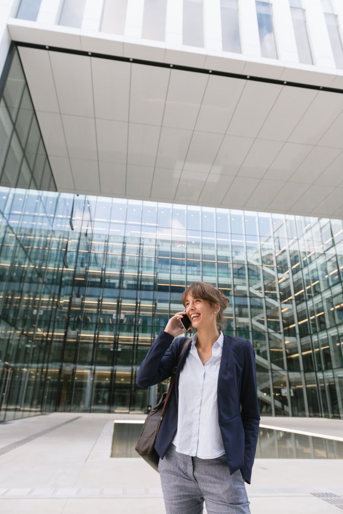 Smiling entrepreneur browsing smartphone outside office building