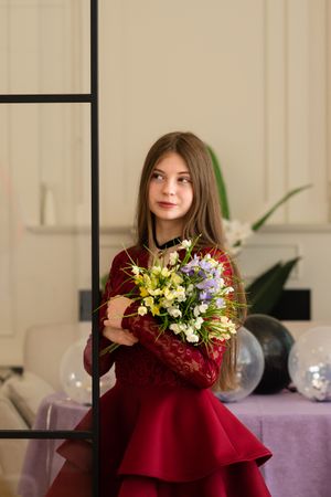 Teen girl in red lace dress holding bouquet of flowers