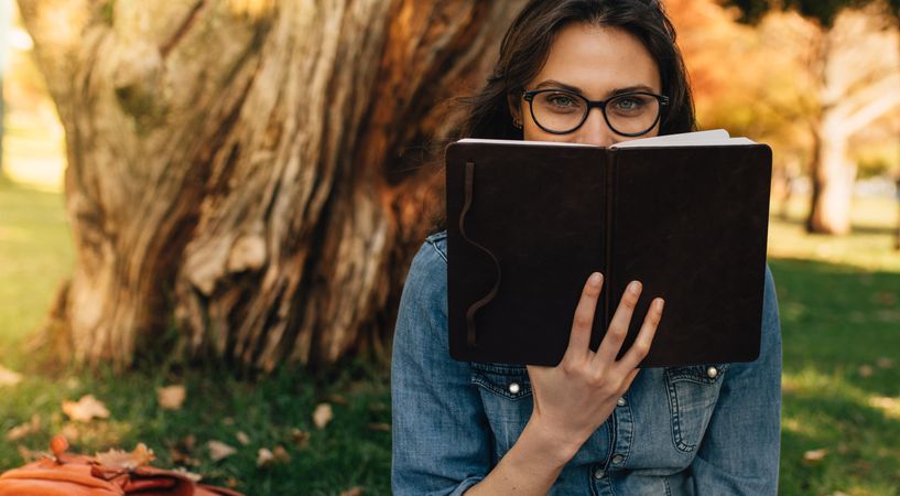 Woman peeking over a book in hand