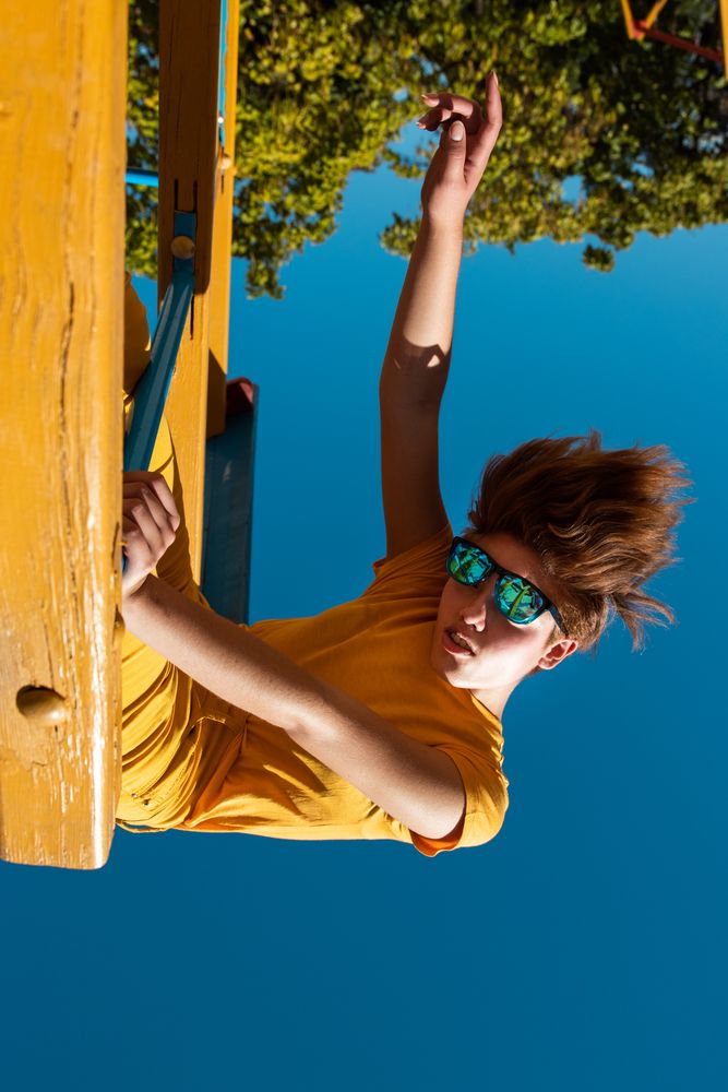 Cool stylish young woman in vibrant clothes on playground