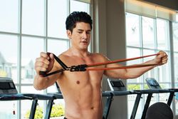 Muscular man exercise with resistance band at fitness studio