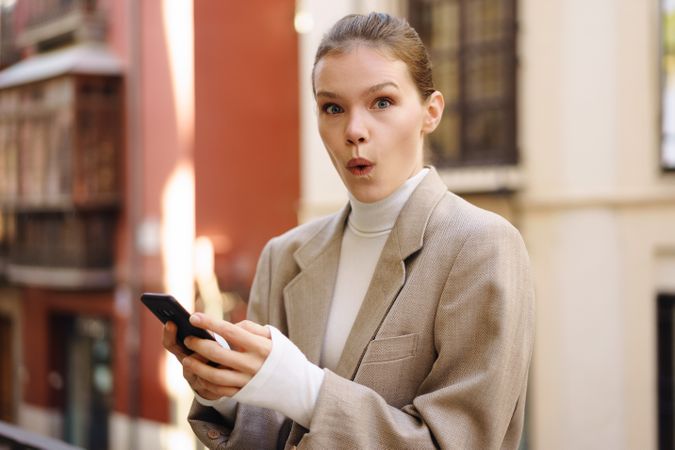 A Happy and Smiling Woman Engaged Deeply with Her Smartphone in a Lively Urban Setting