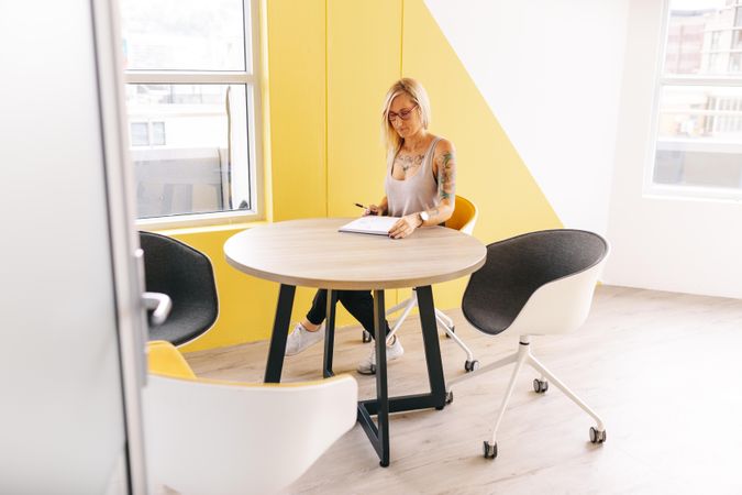 Woman taking notes at a table in a bright modern office