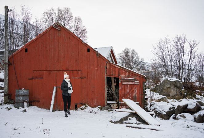 Solitary woman in front of red house in snowy landscape