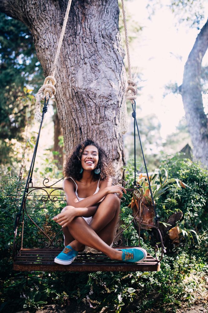 Young woman happily sitting on a swing in a garden