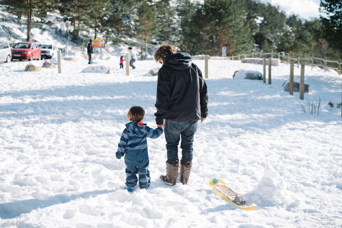 Man with kid walking in snowy yard